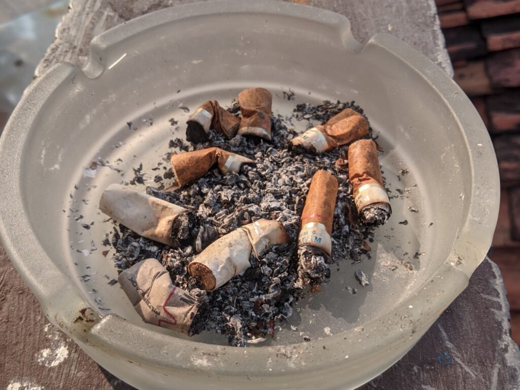 Orang sedang meikmati rokok di tempat terbuka, mencerminkan kebiasaan relaksasi.