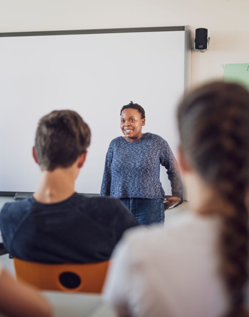 Seorang mahasiswa presentasi di depan kelas dengan percaya diri, menerapkan tips public speaking pemula.