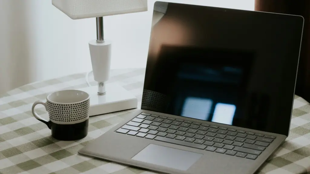 Laptop minimalis di atas meja dengan cangkir kopi, merepresentasikan produk unggulan dalam persaingan raksasa teknologi 2026.